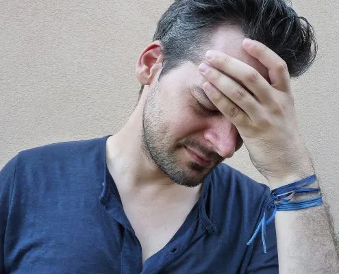 A man who appears to be holding his head with grimace on his face