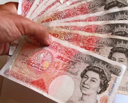 An image of a male holding 11 £50 bank notes.